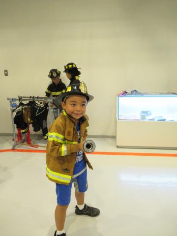 沖縄市防災研修センターで消防士体験をする男の子の写真